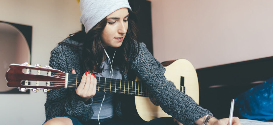 young woman composing music with guitar {{brizy_dc_image_alt entityId=